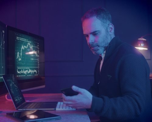 male-stockbroker-using-smart-phone-working-late-at-night-trading-at-home-SBI-349896190 (1)